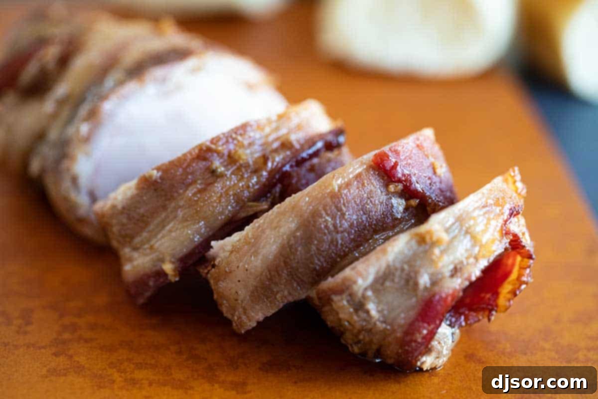 Sliced Bacon Wrapped Pork Tenderloin on a cutting board, ready to be served