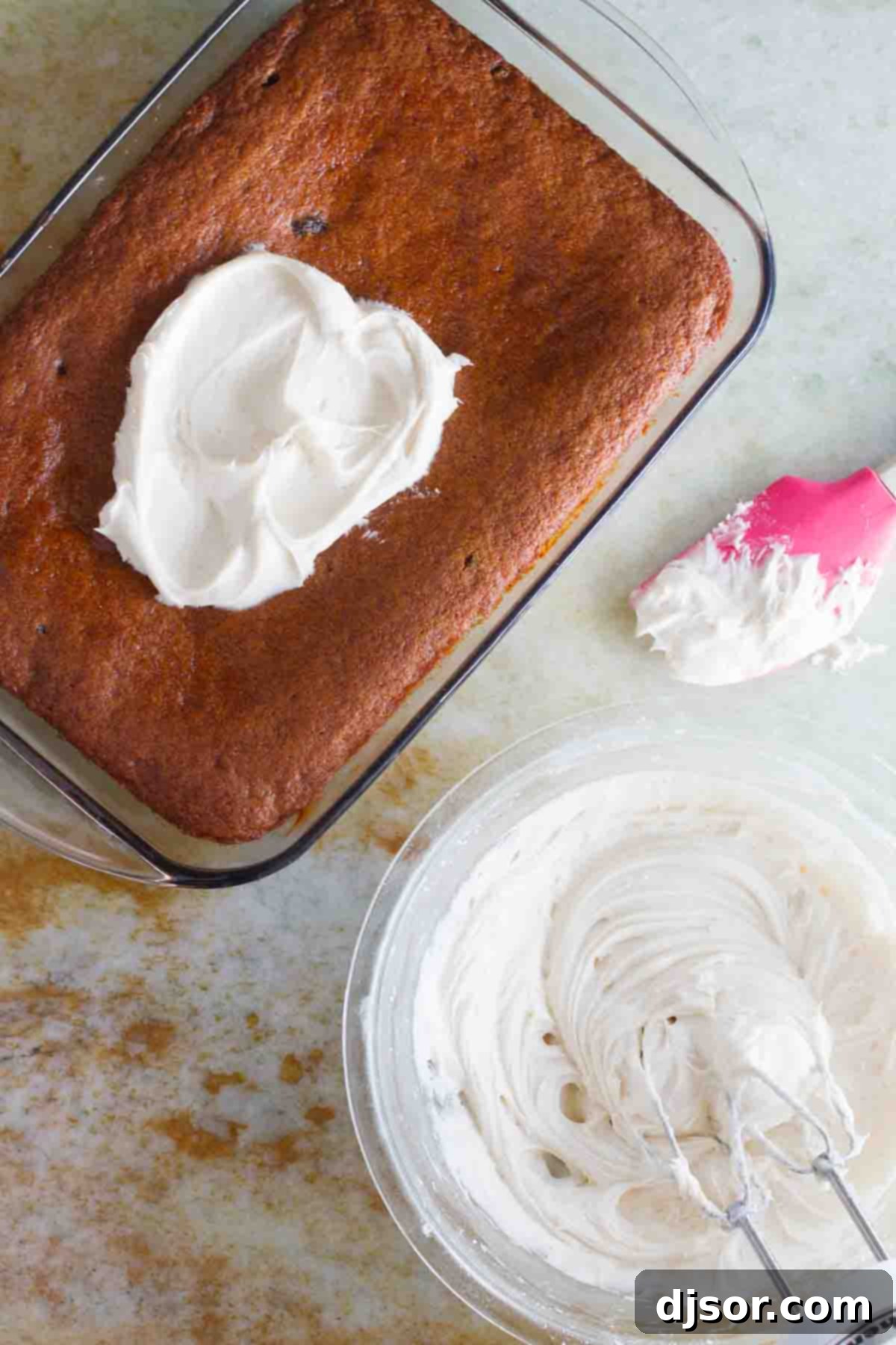 A bowl of luscious cream cheese frosting next to a freshly baked tomato soup spice cake, ready for assembly.