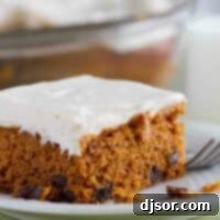 Slice of Tomato Soup Spice Cake topped with creamy cream cheese frosting, inviting a delightful taste.