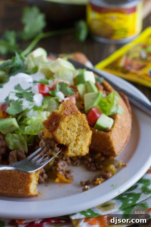 A delicious serving of Taco Cornbread Waffles piled high with ground beef, cheese, lettuce, and sour cream.