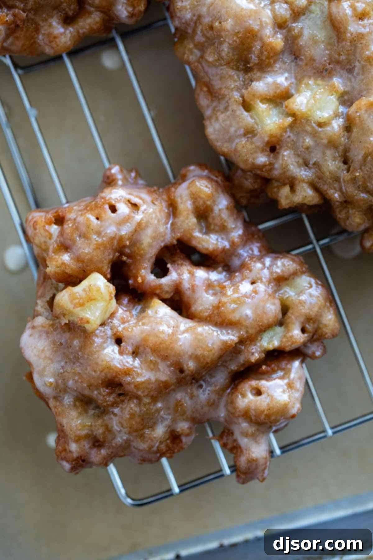 Golden Apple Delights 8 A batch of shiny, glazed apple fritters cooling on a wire rack.