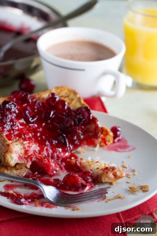 A generous serving of Coconut Crusted Oven Baked French Toast drenched in sweet-tart Cranberry Syrup, a delightful plant-based indulgence.