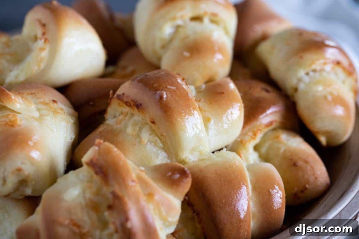 A stack of golden-brown crescent rolls, revealing their soft, cheesy interiors.