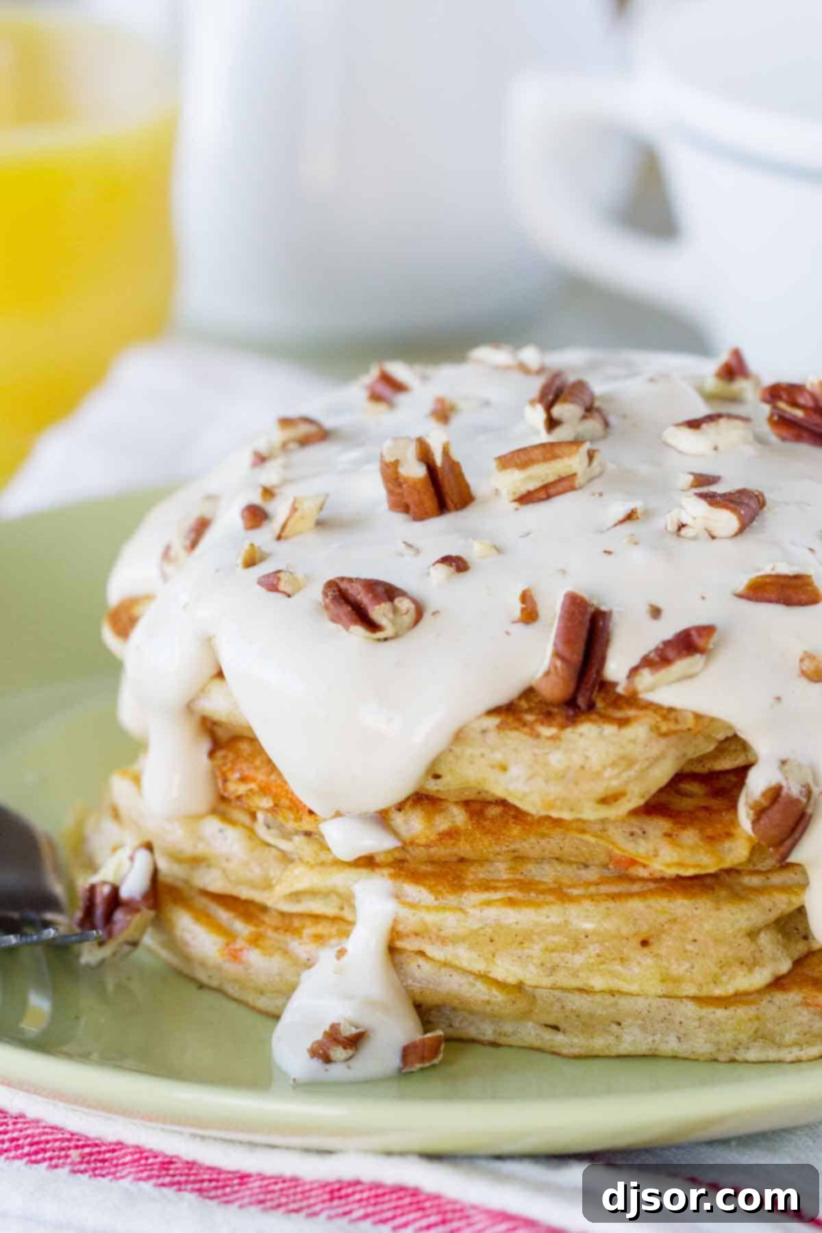 stack of carrot cake pancakes topped with maple cream cheese syrup and nuts