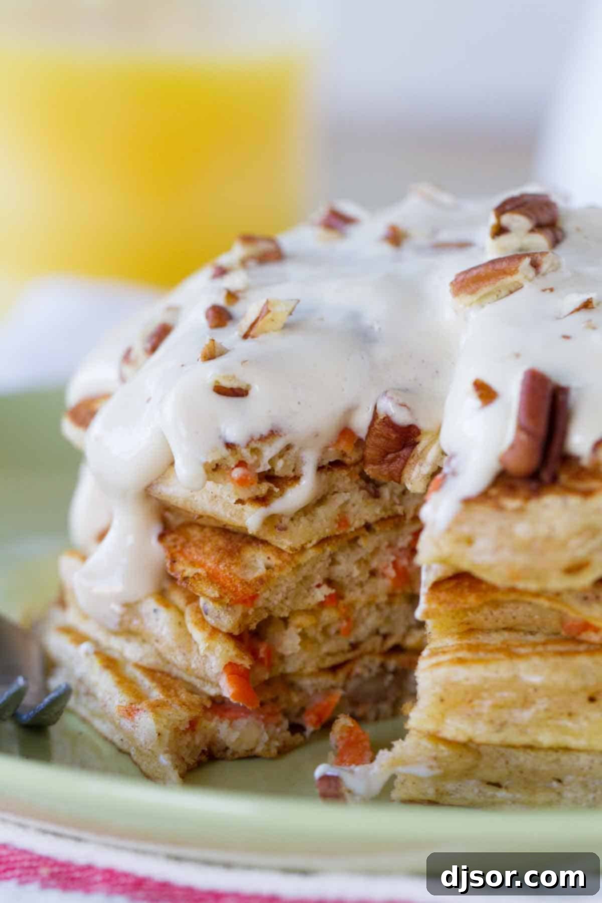 stack of carrot cake pancakes with maple cream cheese syrup with a forkful taken from it to show texture