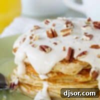 stack of carrot cake pancakes topped with maple cream cheese syrup and nuts.