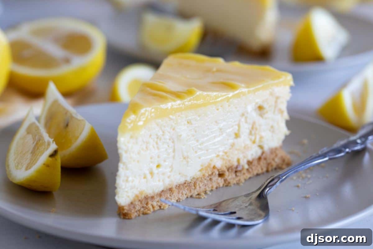 A beautifully presented slice of Lemon Cheesecake, generously topped with glistening lemon curd, with the rest of the cheesecake blurred in the background.