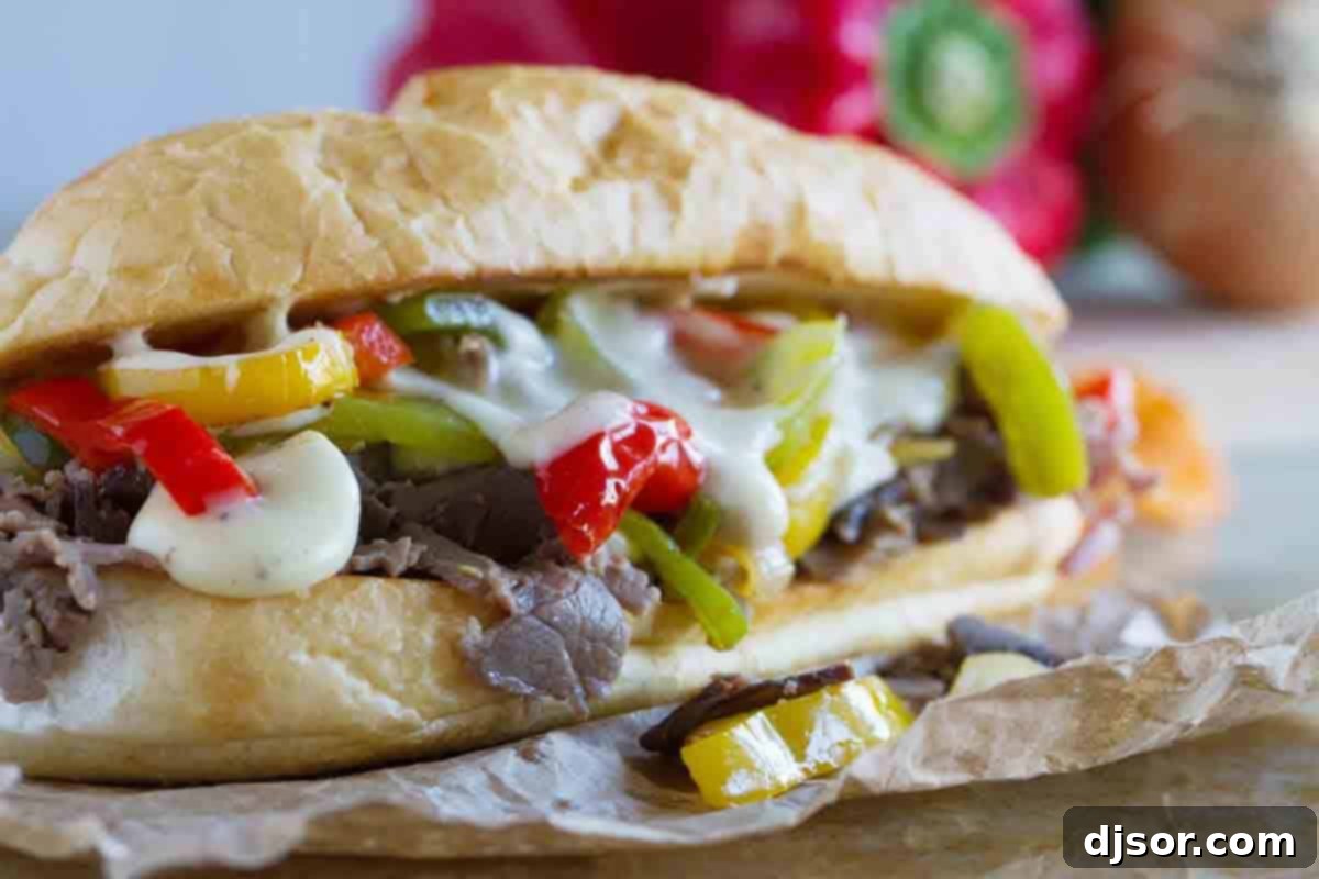 A perfectly assembled cheesesteak sandwich featuring thinly sliced deli roast beef, melted cheese sauce, and sautéed peppers and onions, ready to be enjoyed.