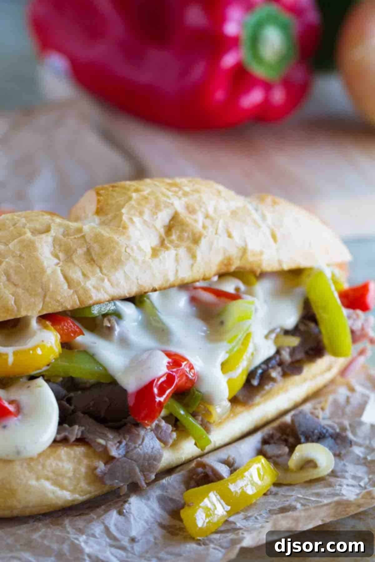 A delectable 30-minute cheesesteak sandwich, showcasing melted cheese sauce generously covering tender roast beef, topped with colorful sautéed bell peppers and onions, all nestled within a toasted sub roll.