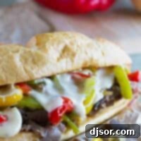 Cheesesteak sandwich with cheese sauce and peppers.