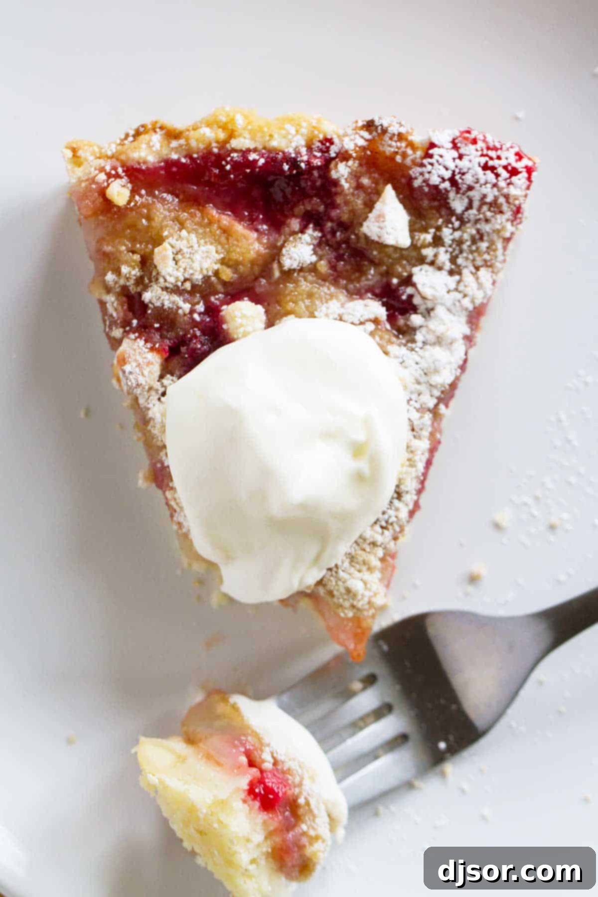 Golden Pear and Raspberry Tart 5 Slice of Pear and Raspberry Tart topped with whipped cream.