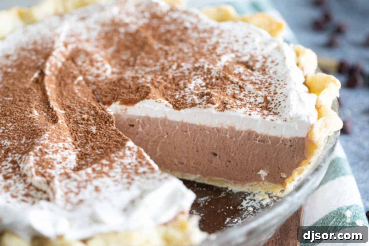 Decadent Chocolate Cream Pie: Rich, Creamy, and Silky Smooth A whole chocolate cream pie with a slice removed, revealing the creamy layers. The pie is topped with whipped cream and a dusting of cocoa powder.