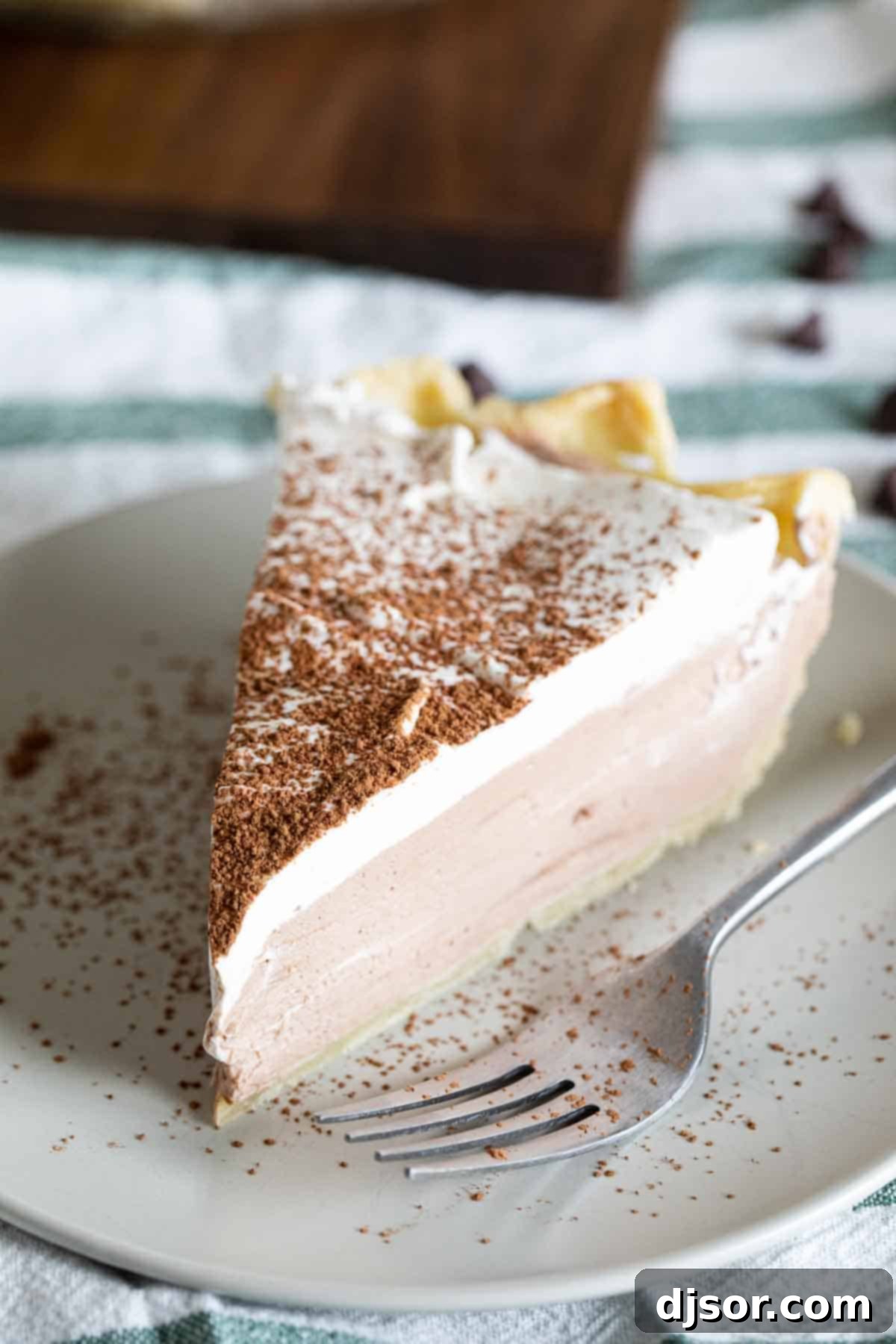 Indulge in a Perfect Slice of Chocolate Cream Pie A perfect slice of chocolate cream pie topped with cocoa powder, ready to be enjoyed.