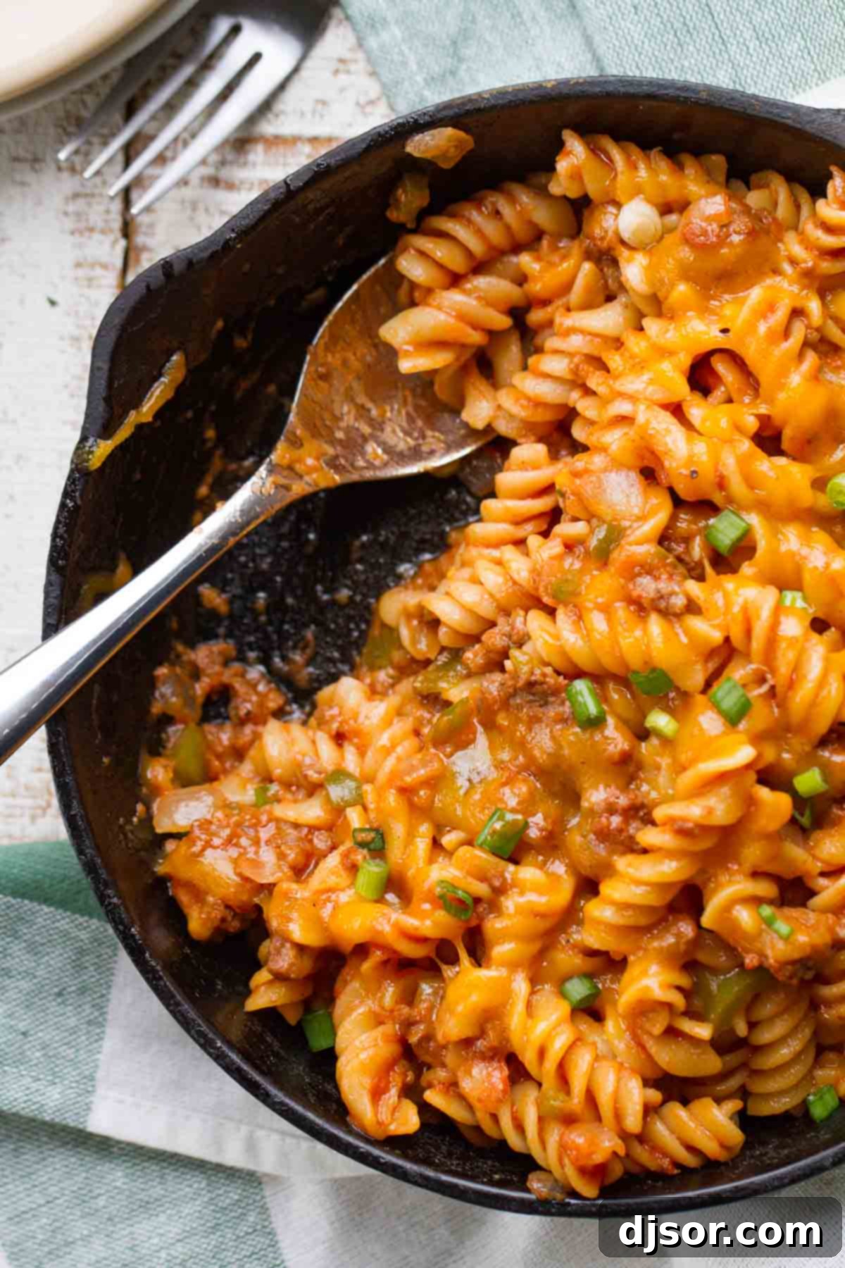Sloppy Joe Pasta in a cast iron skillet with a serving spoon, emphasizing its hearty texture and generous portions.