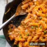 Sloppy Joe Pasta in a cast iron skillet with a serving spoon.