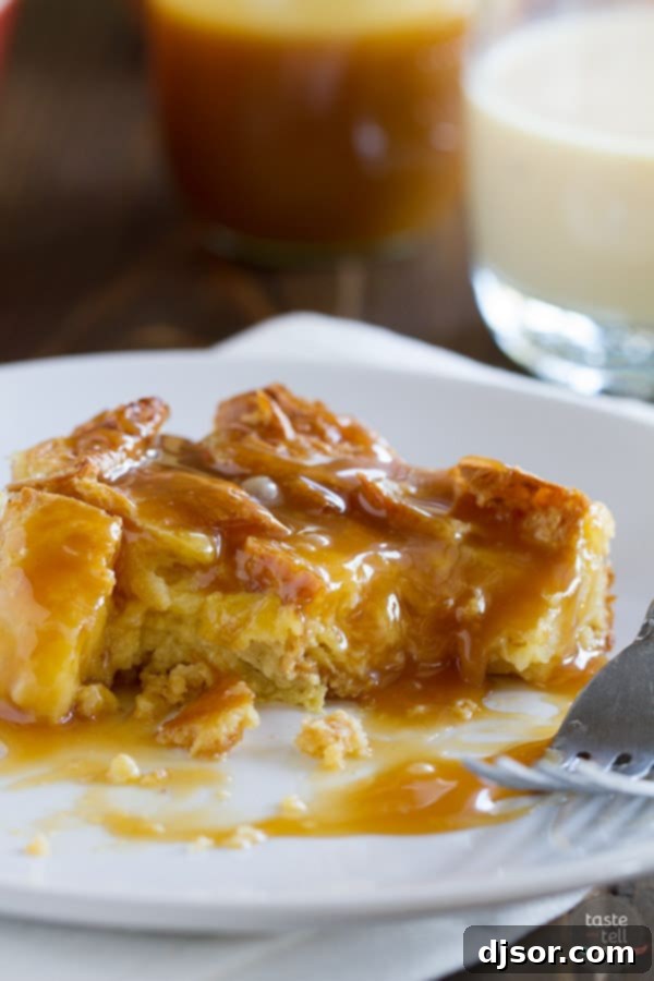 A close-up shot of the Eggnog Croissant Bread Pudding, generously drizzled with rich, golden Caramel Eggnog Syrup, inviting a delicious bite.