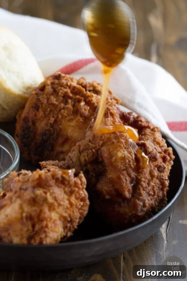 Perfectly golden-brown Honey Fried Chicken pieces arranged with freshly baked buttermilk biscuits and a rich hot honey dipping sauce.