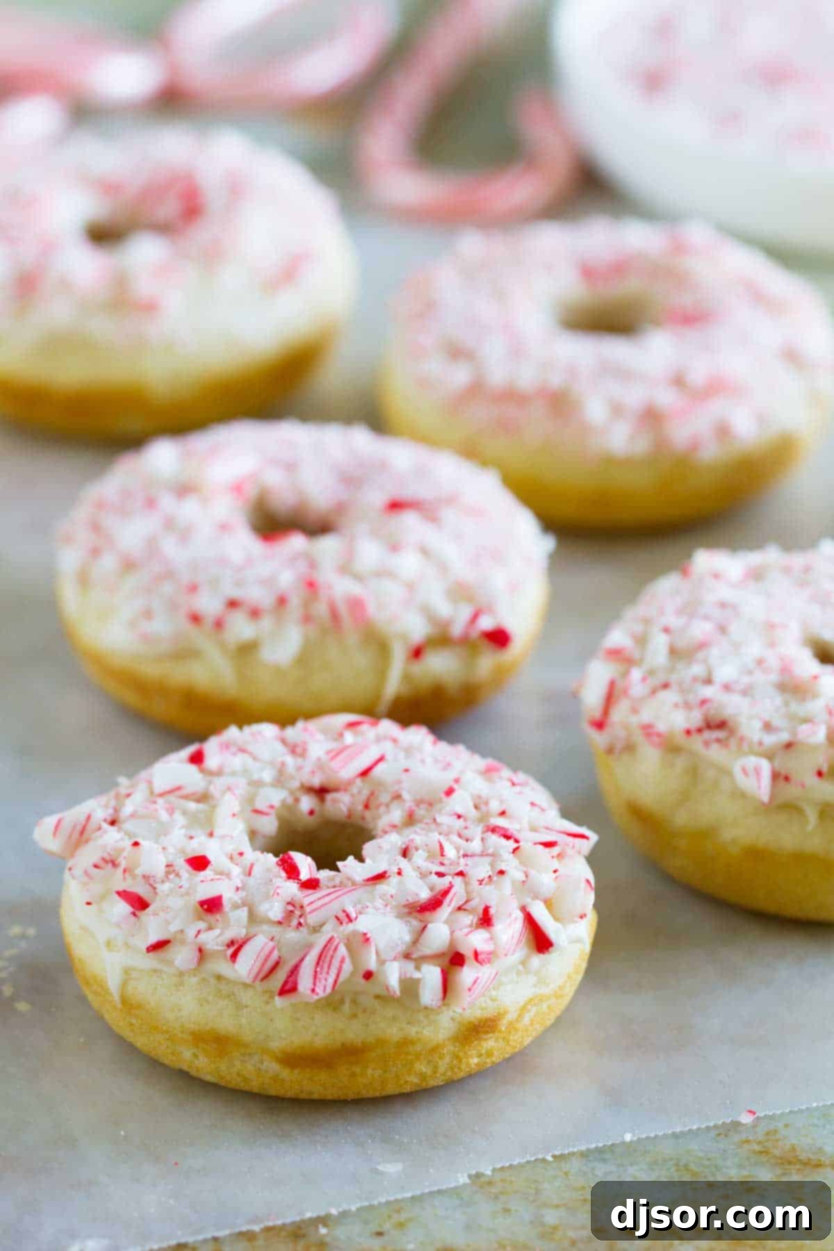 Baked Peppermint Donuts topped with glaze and crushed candy canes, showcasing their festive appeal.