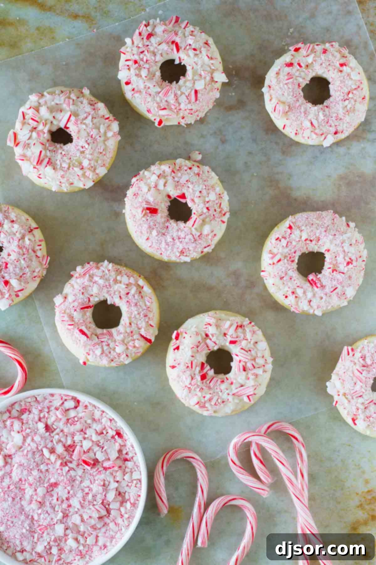 Baked Peppermint Donuts with crushed candy canes and whole candy canes on the side, highlighting their appeal.