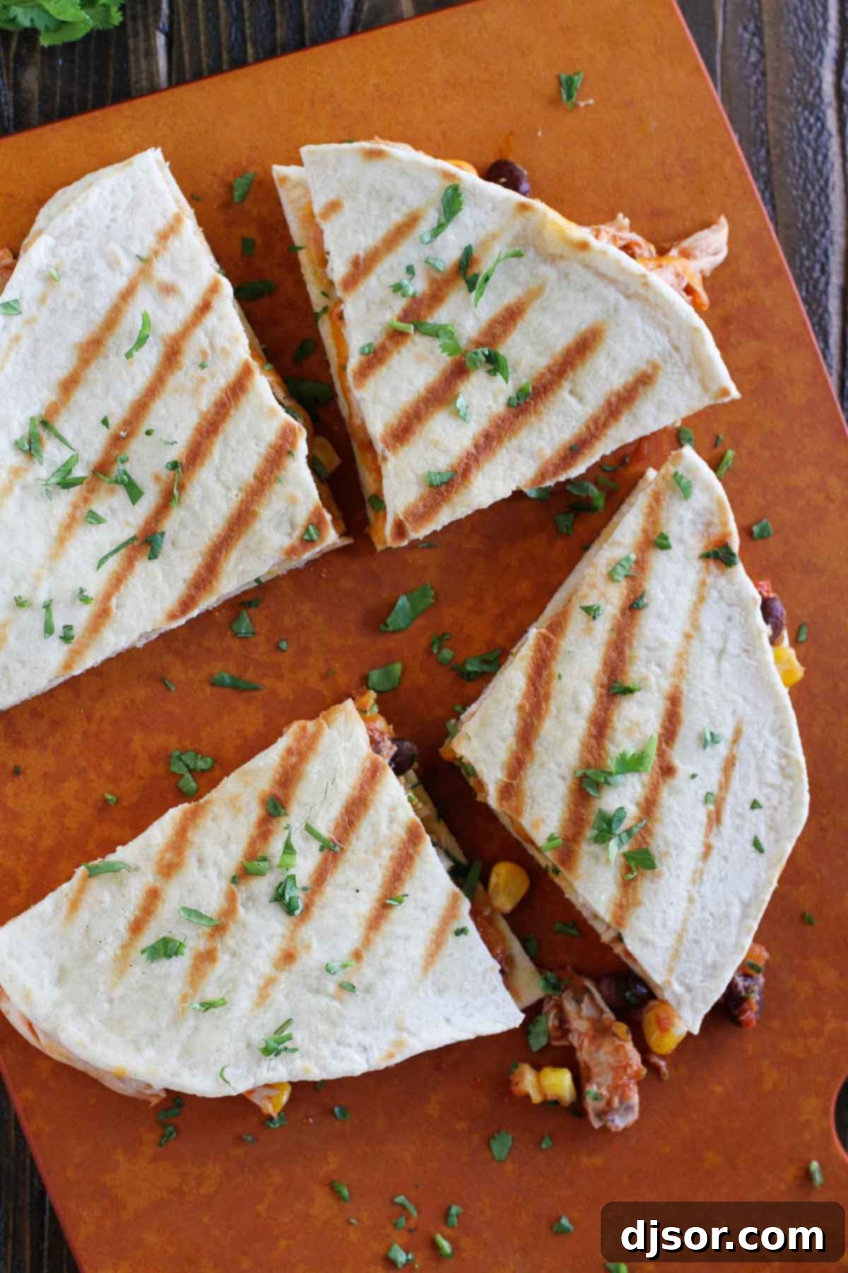 Leave the tortillas behind - these Grilled Chicken Quesadillas turn frozen rolls into flatbread! Grill the flatbread with a delicious chicken filling for the perfect grilling recipe. Grilled Chicken Quesadillas sliced into quarters, showcasing the delicious filling and crispy crust.