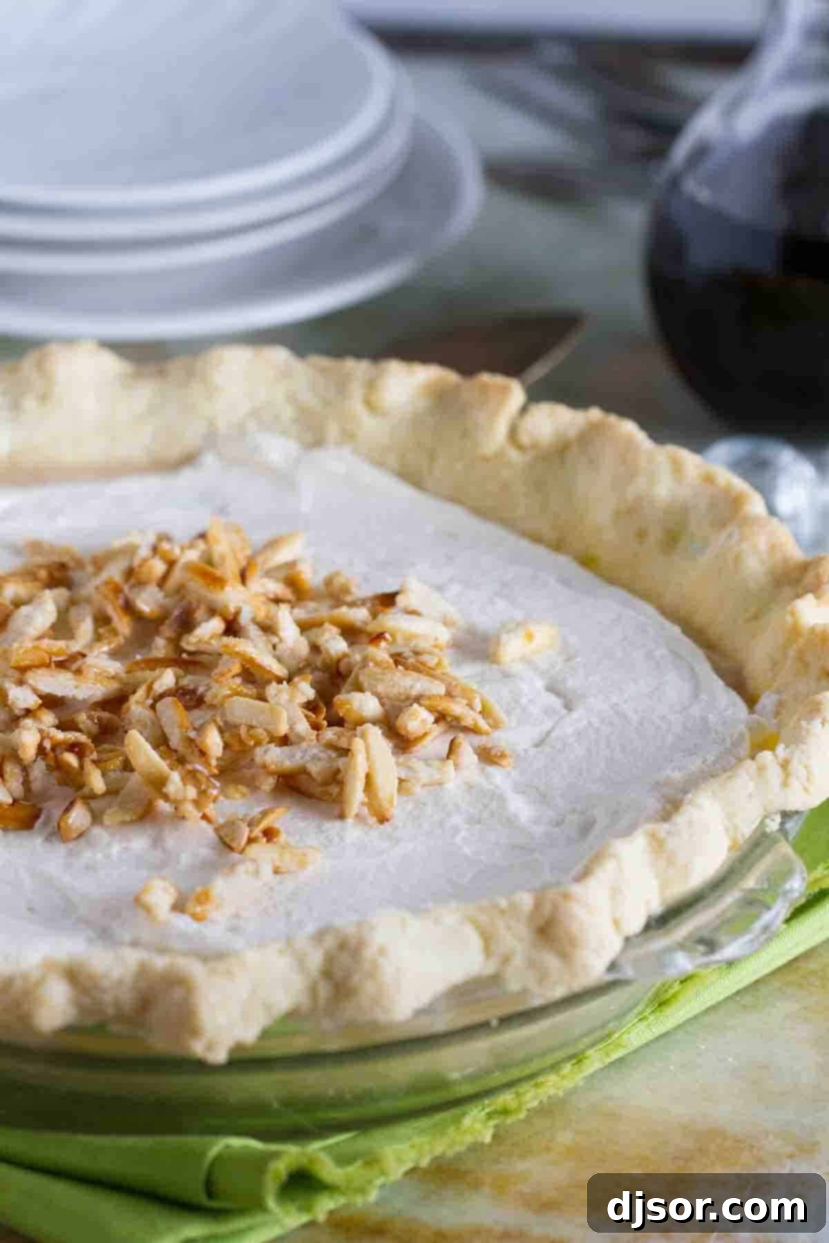 Whole Maple Cream Pie with Almonds A full, perfectly prepared Maple Cream Pie, beautifully topped with a swirl of whipped cream and a generous scattering of glistening sugared almonds, set against a rustic background.