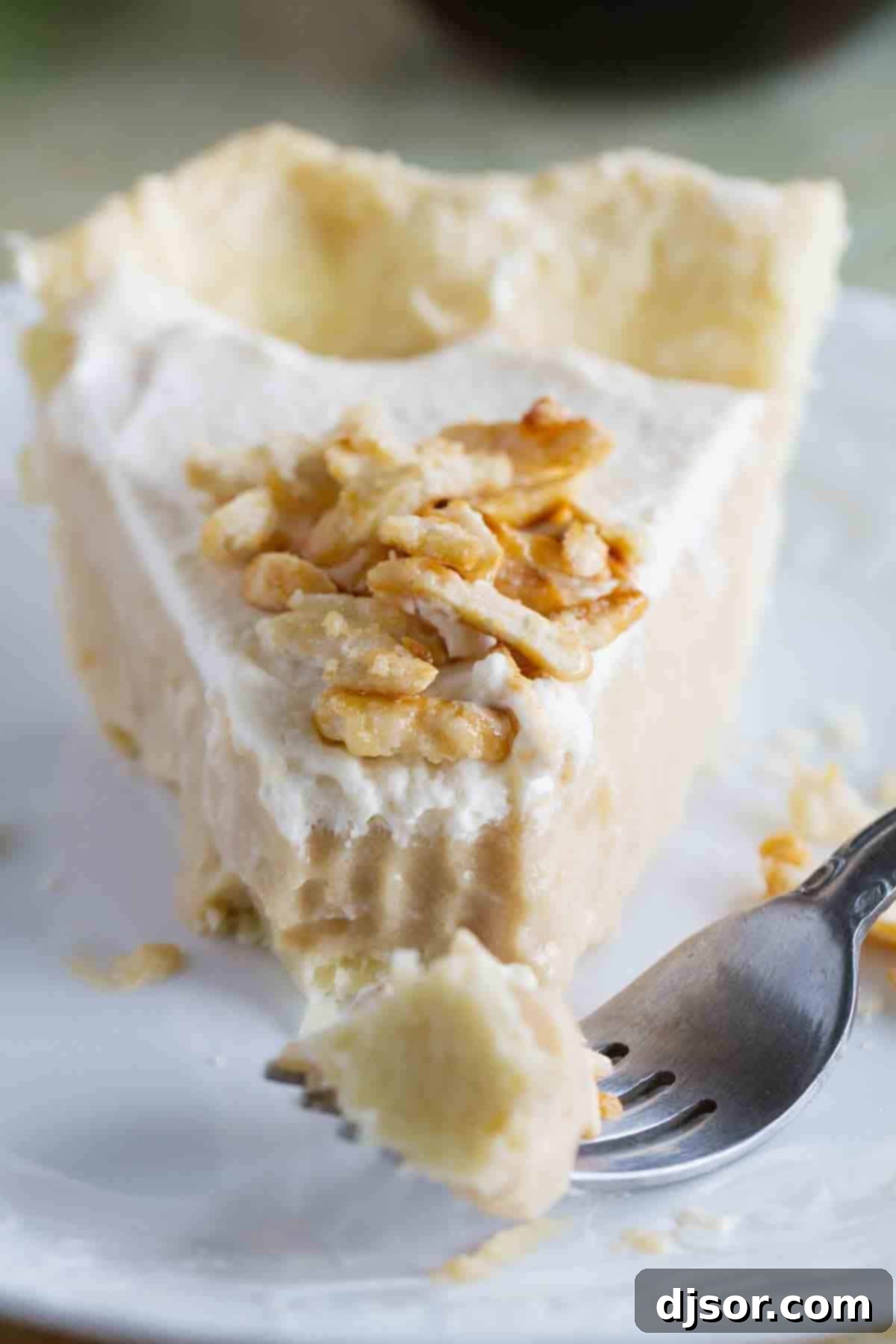 Maple Cream Pie with Fork A delectable slice of Maple Cream Pie on a plate, with a fork gently scooping a creamy bite, highlighting the layers of crust, maple filling, whipped cream, and sugared almonds.