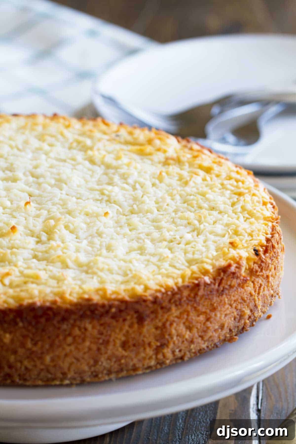 A whole Coconut Custard Pie, beautifully golden brown, displayed on a elegant serving platter.