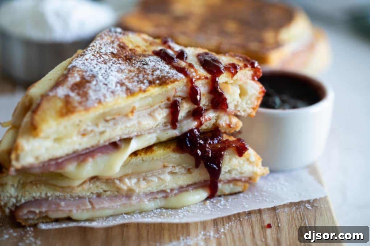 Decadent Monte Cristo Sandwich, cut in half, drizzled with raspberry jam and powdered sugar