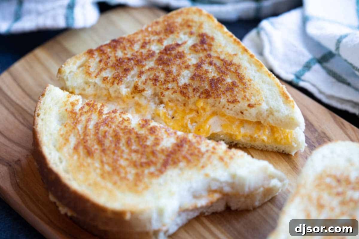 Perfectly sliced Grilled Cheese Sandwich revealing gooey melted cheese, on a cutting board