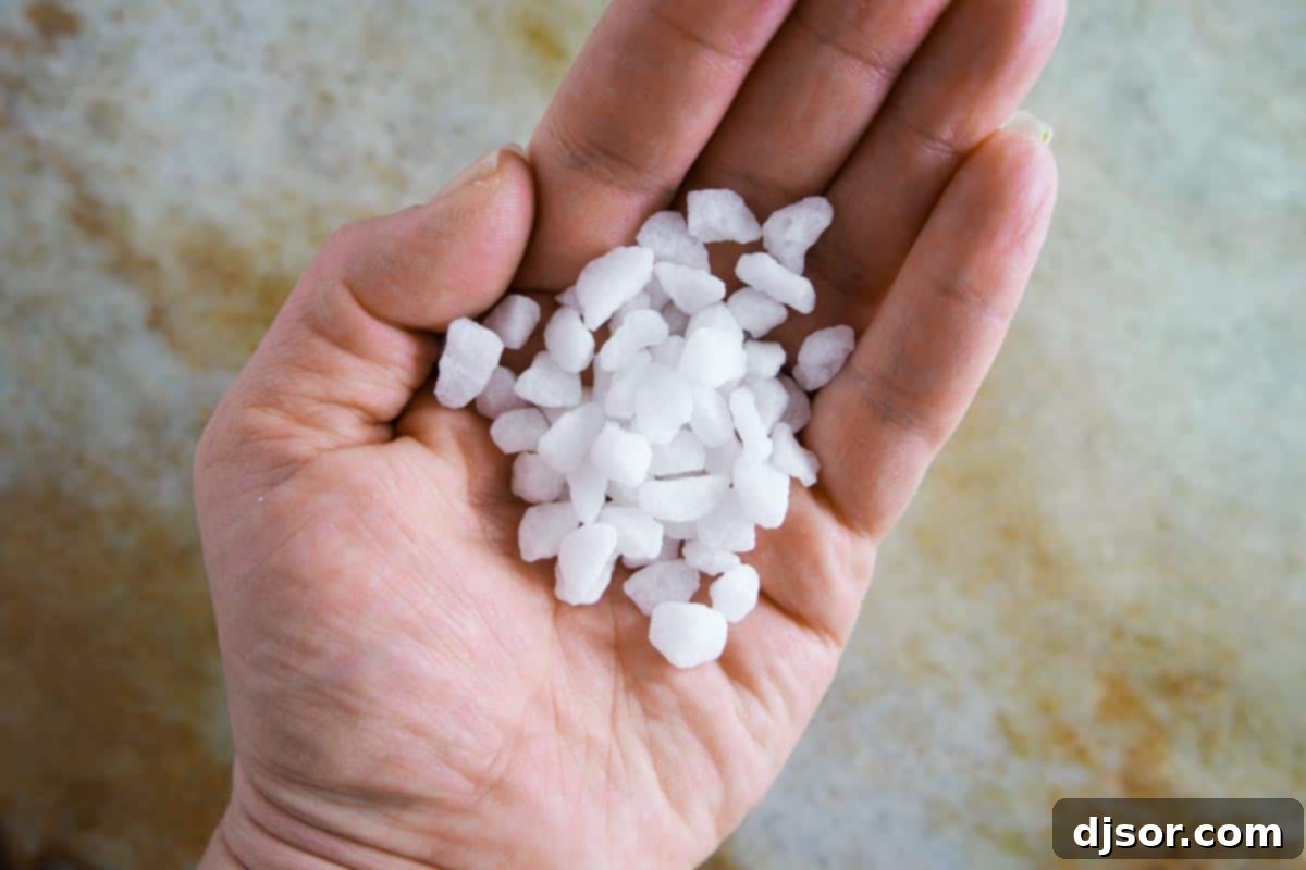 Bring a taste of Belgium into your kitchen with these Liege Waffles! A wonderful special breakfast or afternoon treat, these yeasted sugar waffles are irresistible. A close-up shot of a handful of coarse, irregular pearl sugar granules, highlighting their unique texture.