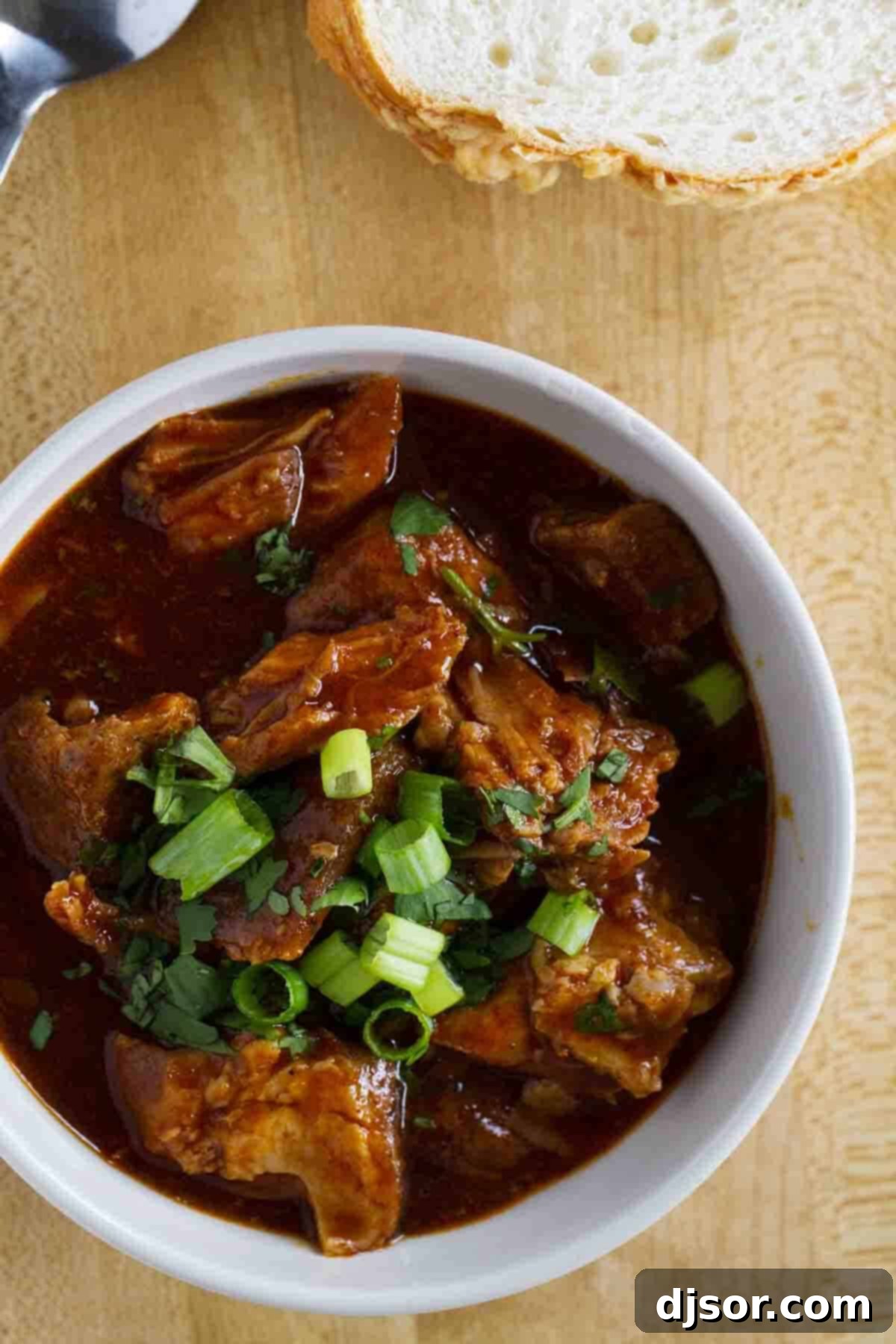 New Mexican Red Pork Chili with Cilantro and Green Onions Close-up of New Mexican Red Pork Chili in a bowl, topped generously with chopped green onions and fresh cilantro.