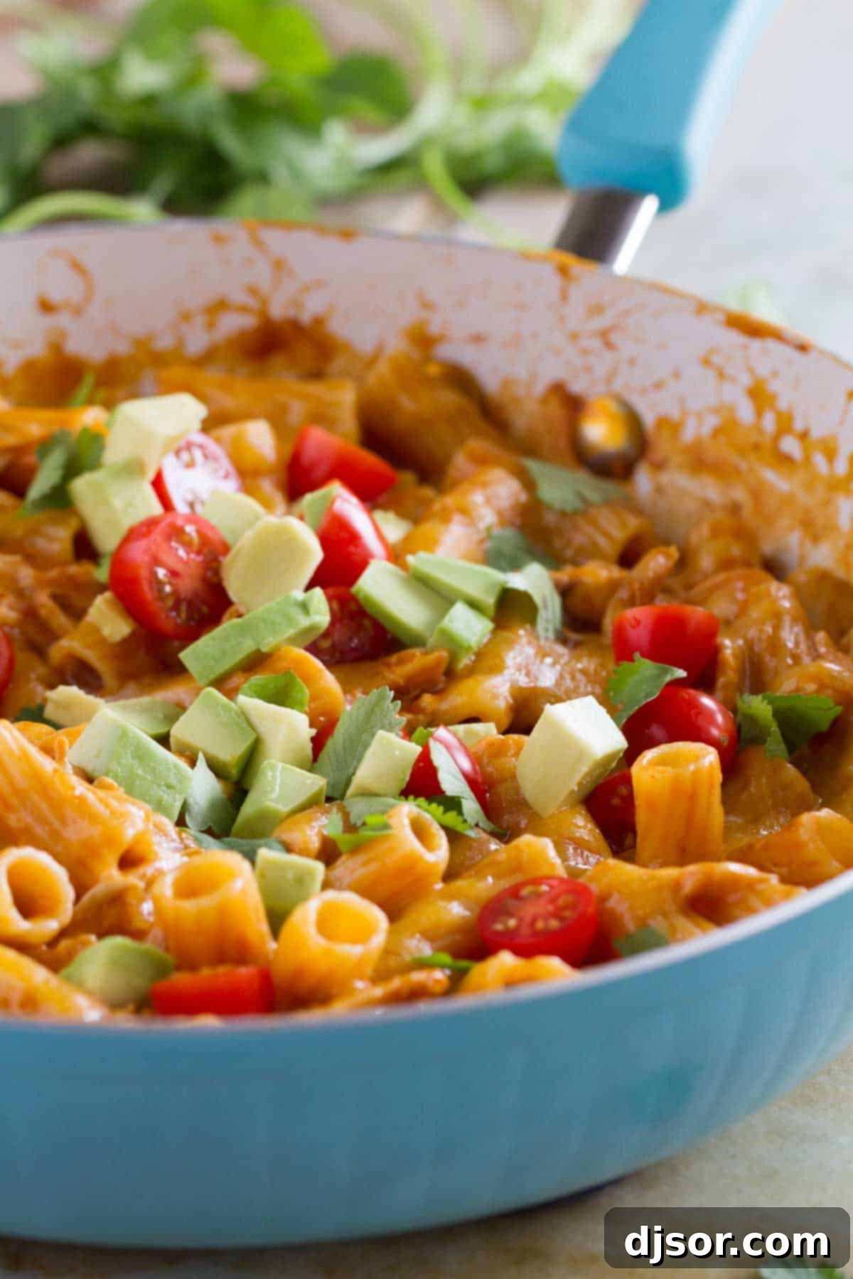 Great flavors come together in one pan in this One Pan Enchilada Pasta. It’s got the Tex-Mex flavors that mom and dad love, while being mild enough for the kids. And there’s only one pan to clean when it’s done! One pan enchilada pasta in a blue skillet, topped with tomatoes and avocado, ready to be served.