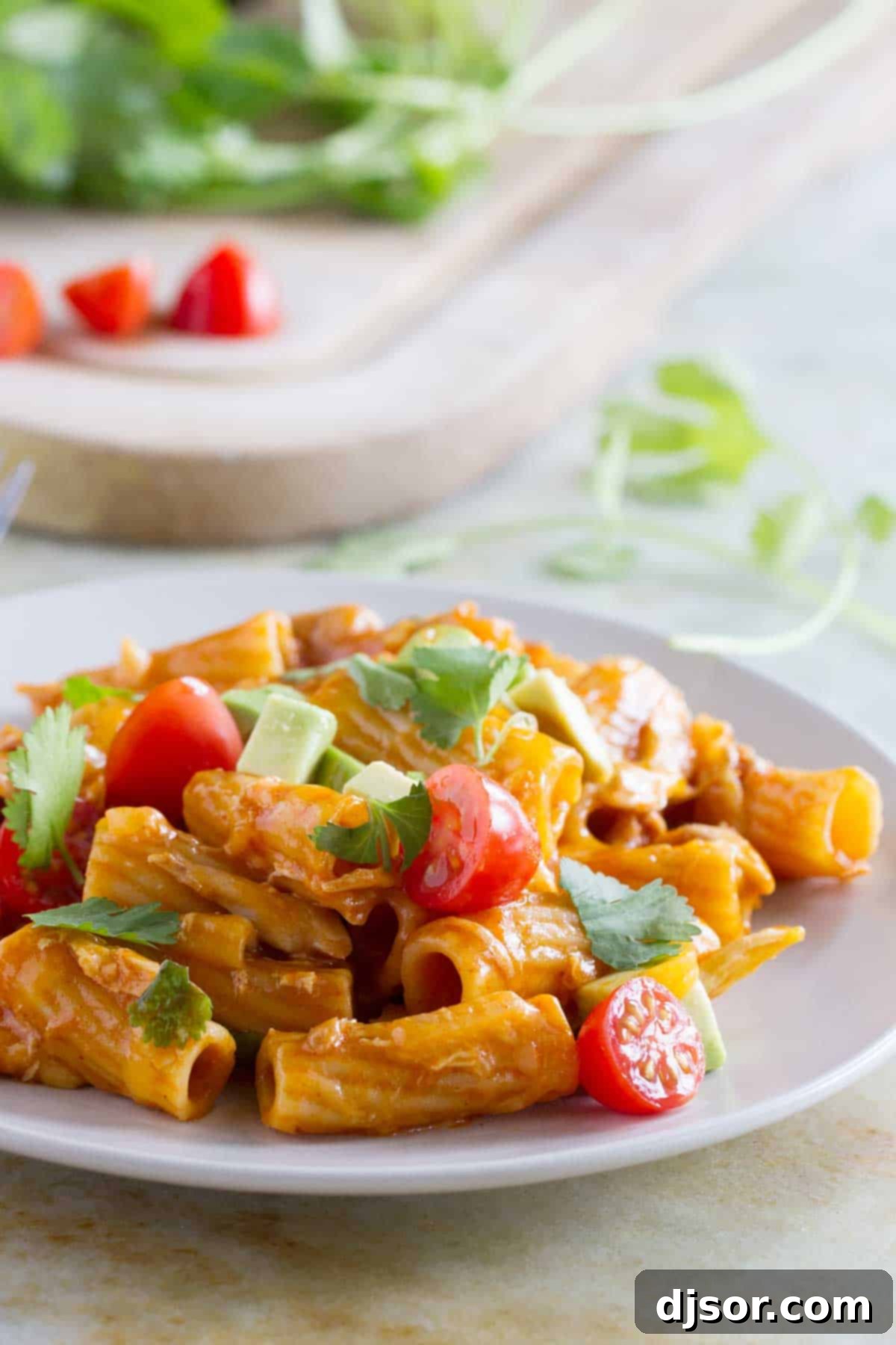 Great flavors come together in one pan in this One Pan Enchilada Pasta. It’s got the Tex-Mex flavors that mom and dad love, while being mild enough for the kids. And there’s only one pan to clean when it’s done! Enchilada pasta on a plate, generously topped with avocado, tomatoes, and cilantro.