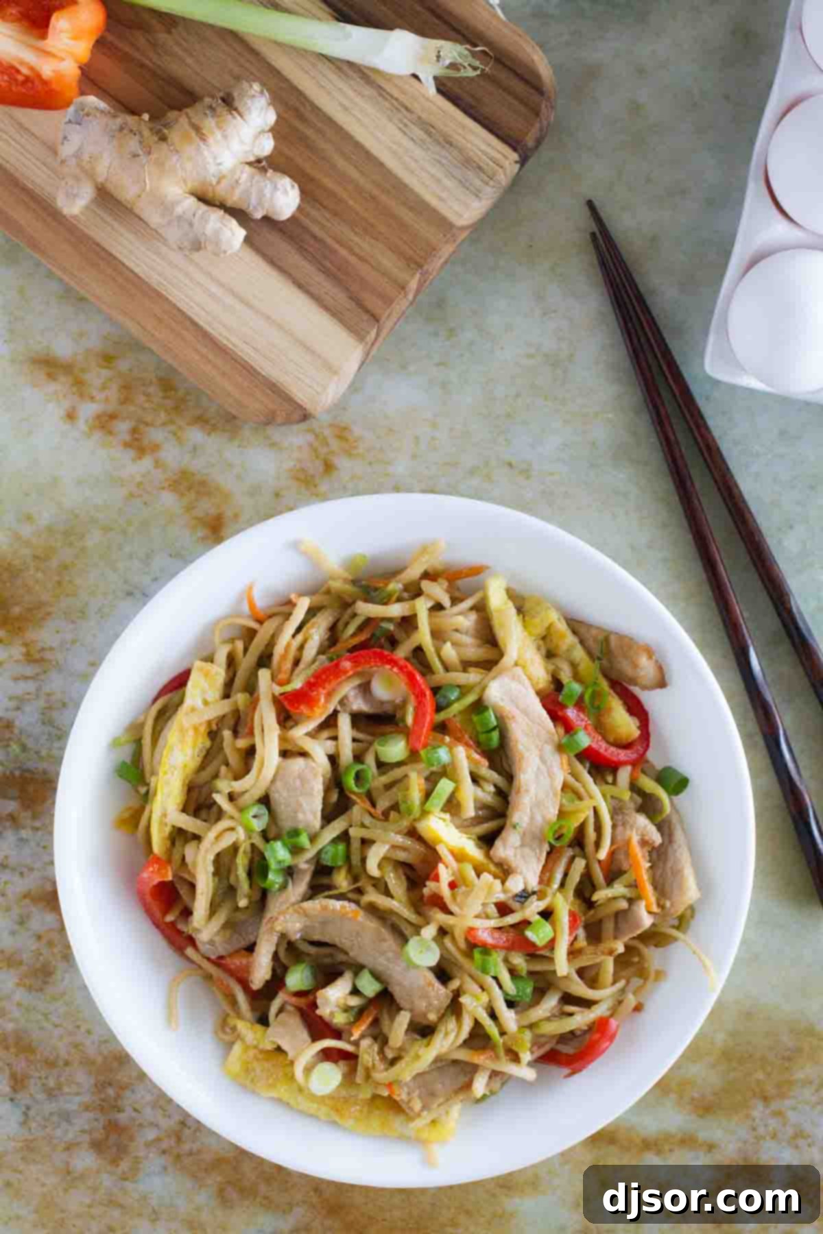 Overhead view of a bowl of Egg and Pork Lo Mein, showing the generous portion and vibrant ingredients.