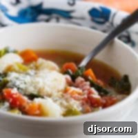 Bowl of Minestrone with Gnocchi with a spoon in it.