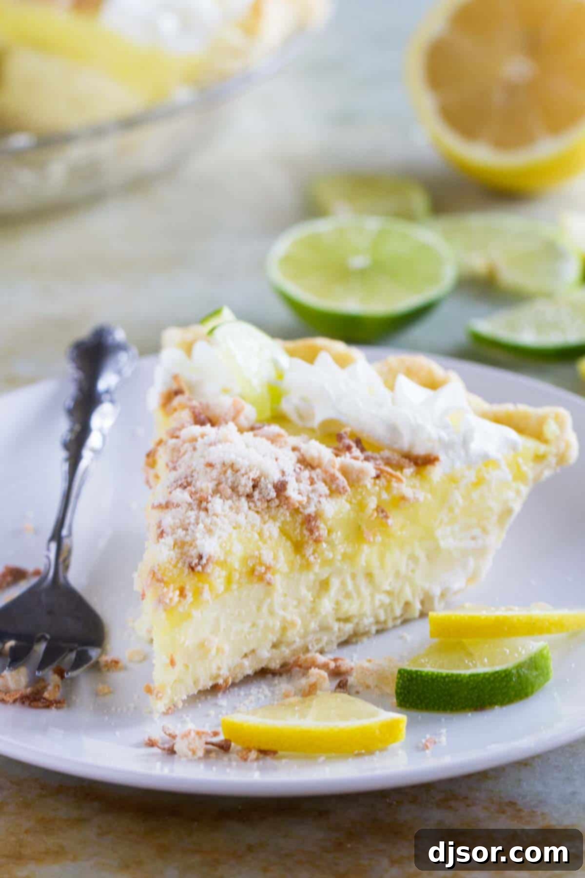 A perfectly sliced piece of Caribbean Truffle Pie on a white plate, showcasing its distinct layers of crust, creamy filling, and a topping of whipped cream and toasted coconut.