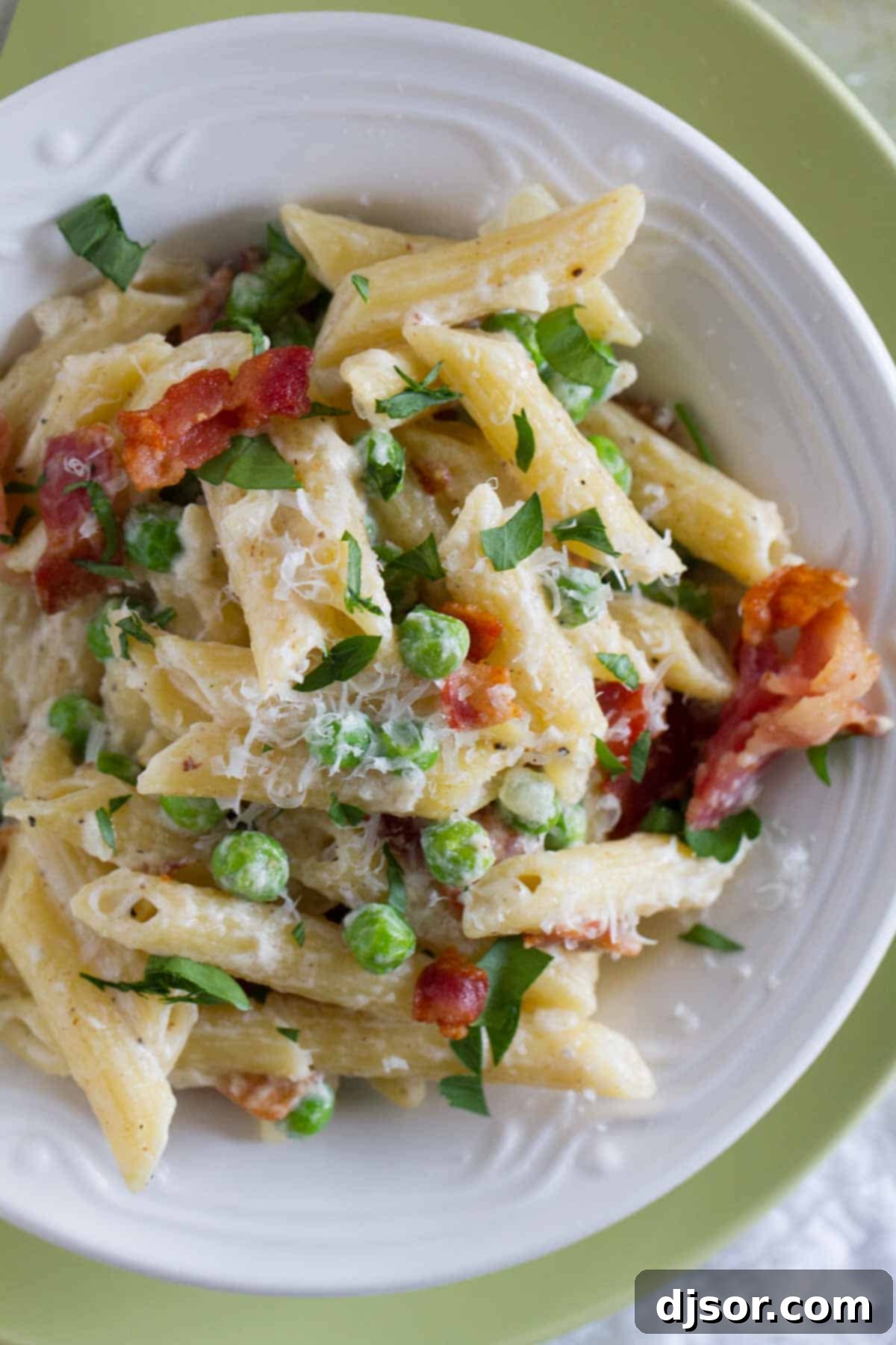 Smoky Bacon Sweet Pea Skillet Pasta 4 A shallow bowl showcasing a generous portion of creamy pasta with bits of bacon and green peas, ready to be served.