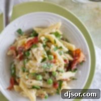 Smoky Bacon Sweet Pea Skillet Pasta 5 White bowl with one pan pasta with bacon and peas, topped with parmesan cheese.