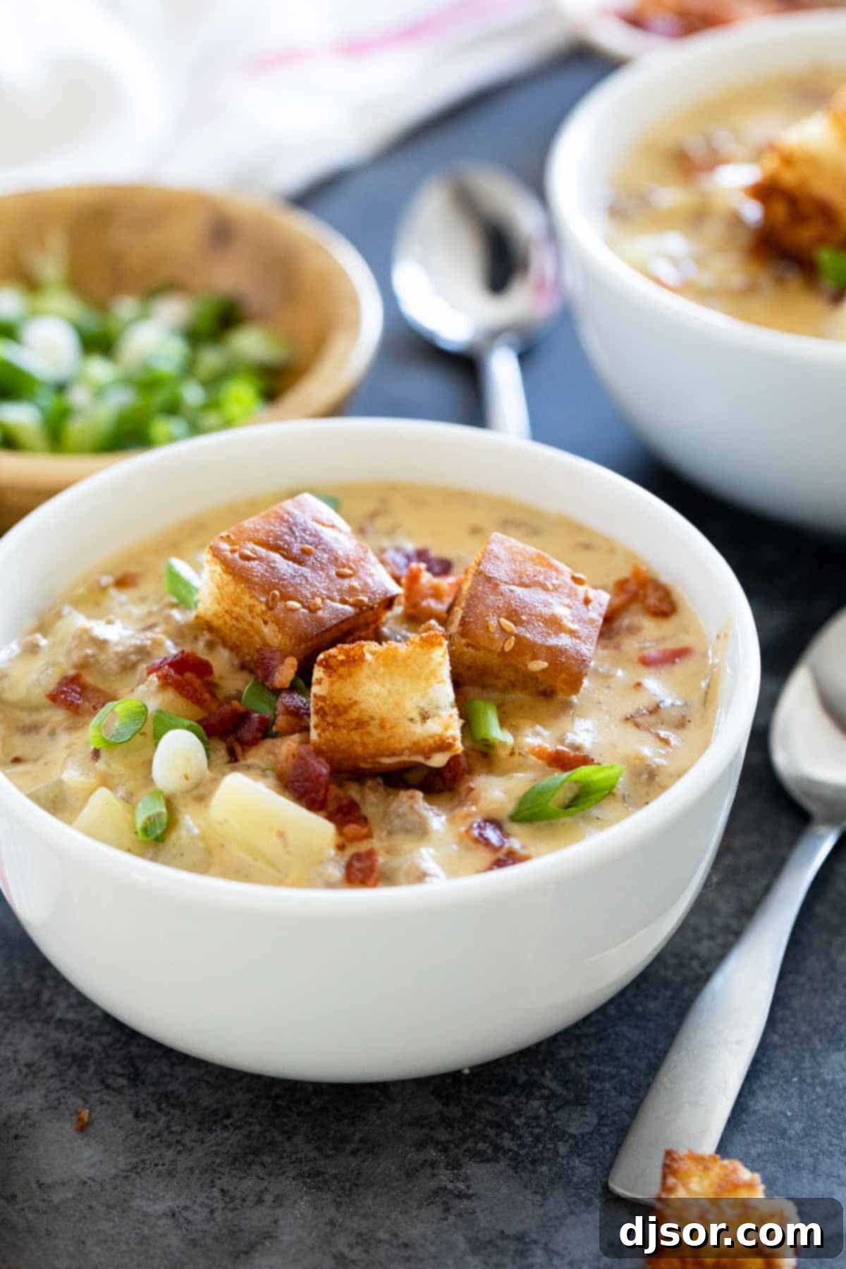 A close-up view of a bowl of bacon cheeseburger chowder, highlighting the tender potato chunks, crispy bacon pieces, and the rich, creamy texture of the soup, inviting a comforting meal.