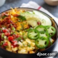 Loaded breakfast bowl, with roasted potatoes, scrambled eggs, bacon, and lots of toppings.