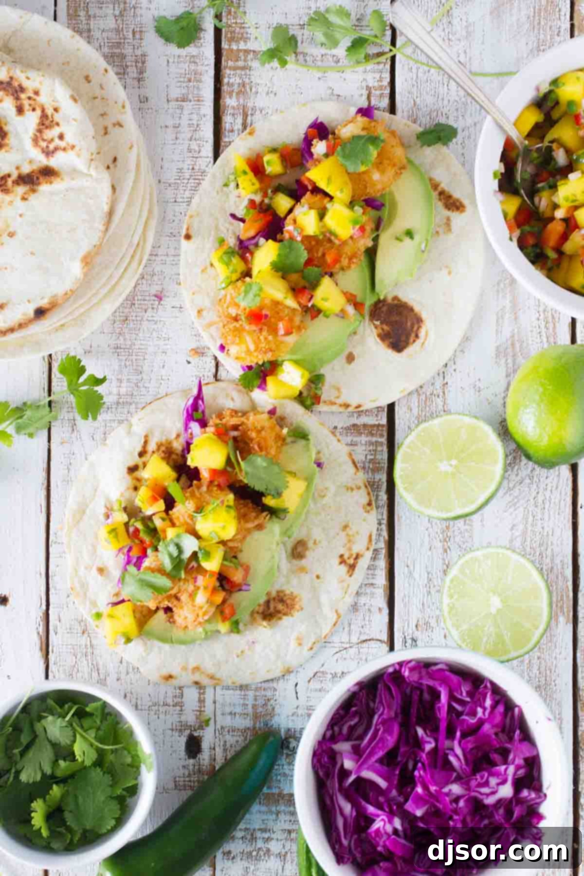 Close-up shot of tortillas topped with golden brown coconut shrimp and vibrant mango salsa, showcasing the texture and color of the dish.