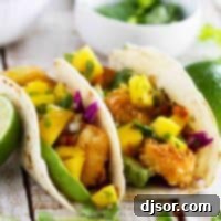 Two coconut shrimp tacos topped with mango salsa and avocado