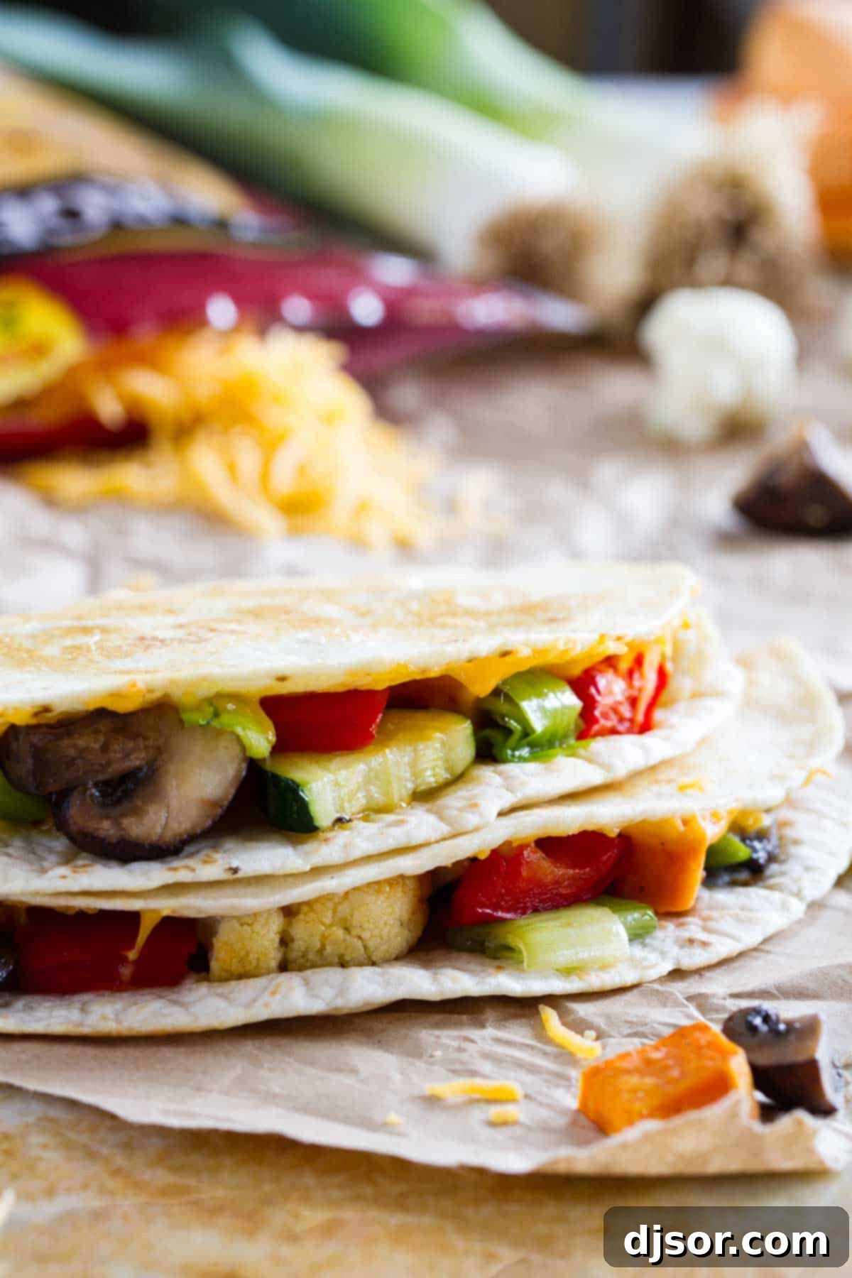 Slices of a perfectly cooked, golden-brown veggie quesadilla stacked on top of each other, revealing a vibrant filling of roasted vegetables and melted cheese.