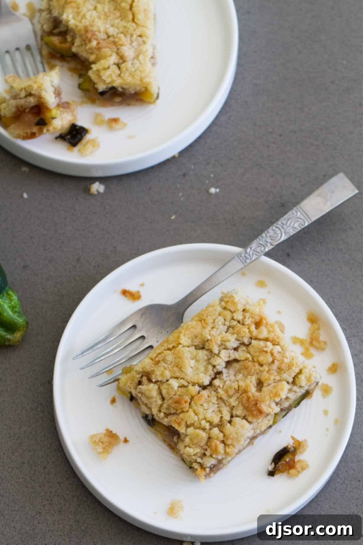 Enjoy the comforting aroma and taste of these Zucchini Cobbler Bars, a perfect dessert for any season. An overhead view of a baking dish filled with freshly baked Zucchini Cobbler Bars, revealing their golden-brown crumb topping and ready to be served.