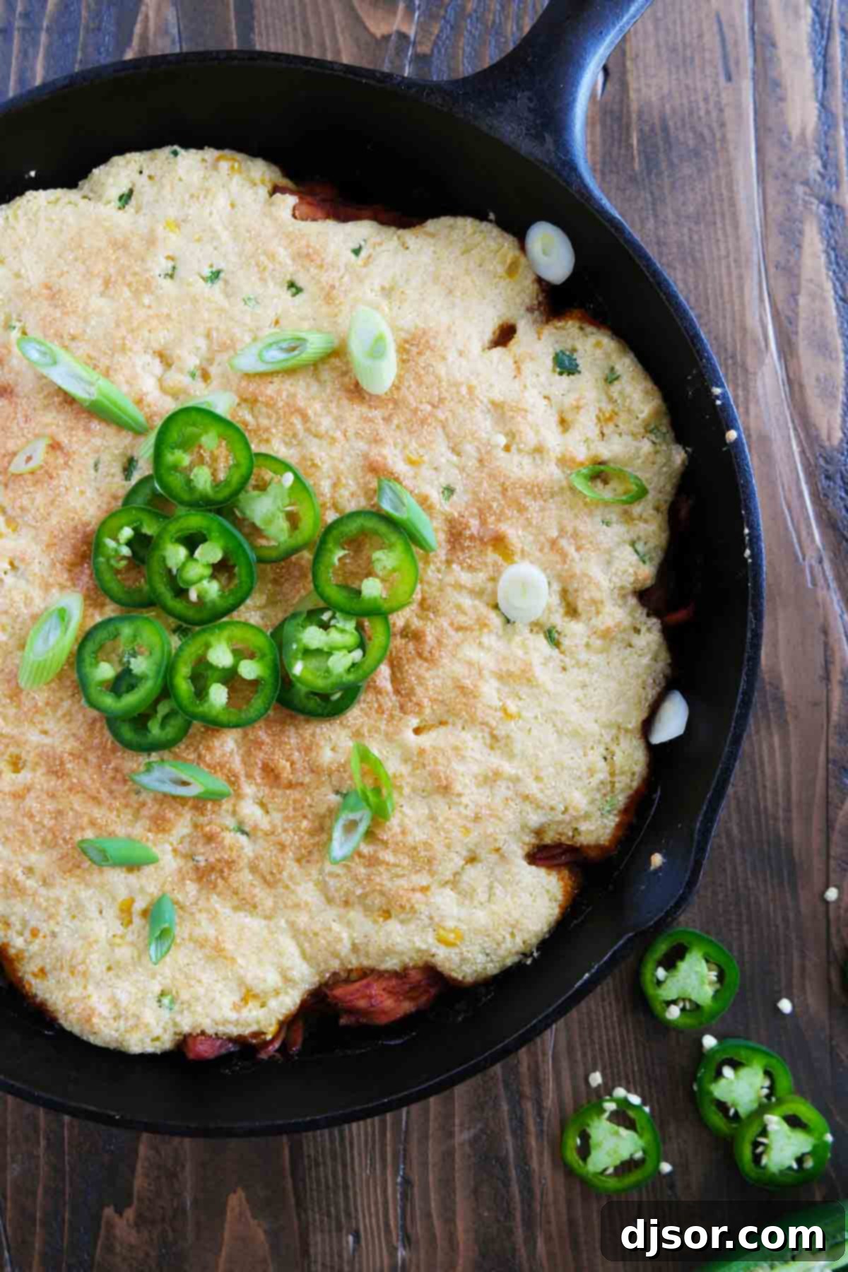 Cornbread-Crusted BBQ Pork Casserole 3 Cornbread Topped BBQ Pork simmering in a rustic cast iron skillet, ready for baking.