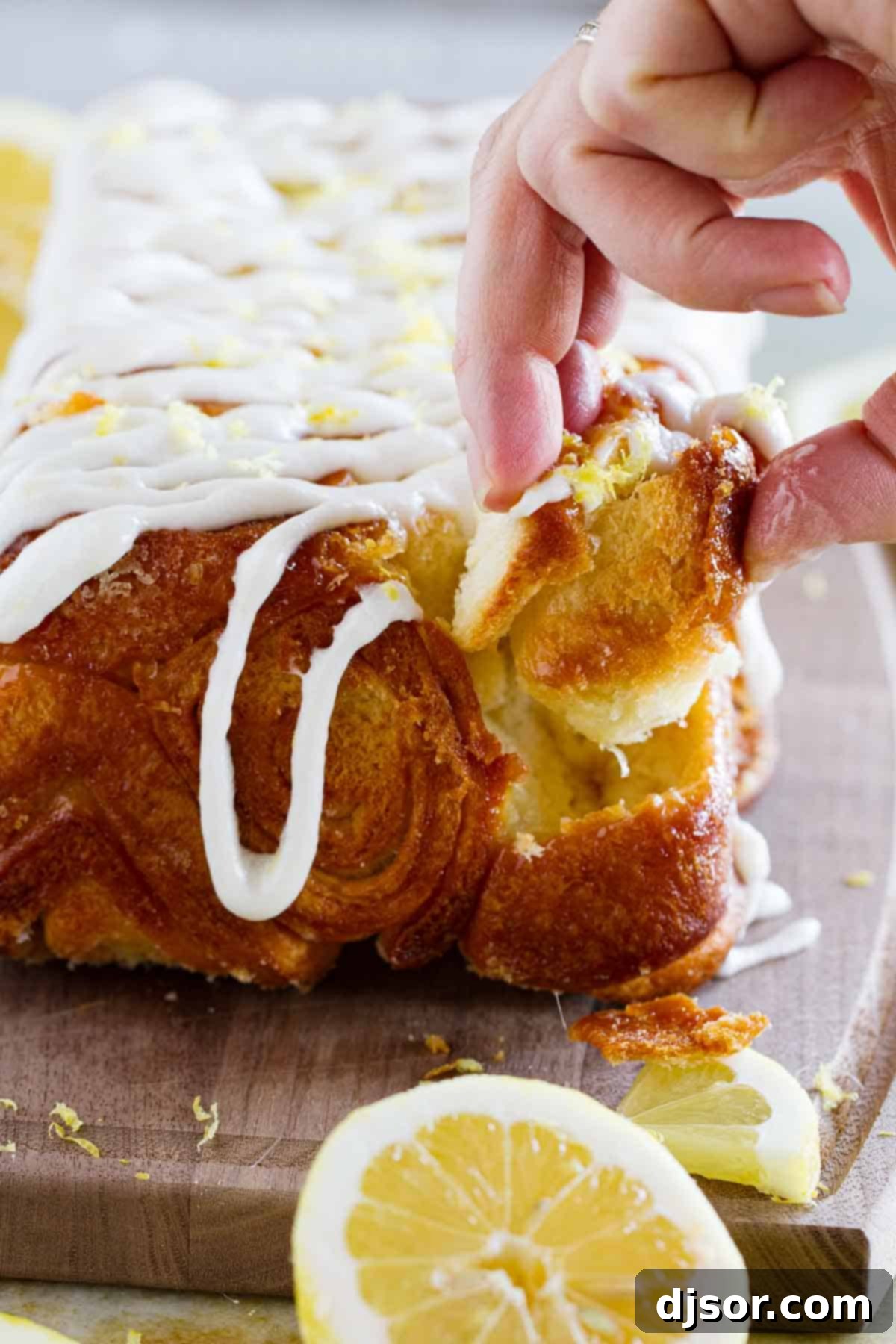 Bright Lemon Swirl Pull-Apart Loaf 7 Fingers pulling a piece of lemon roll pull apart bread from the loaf.