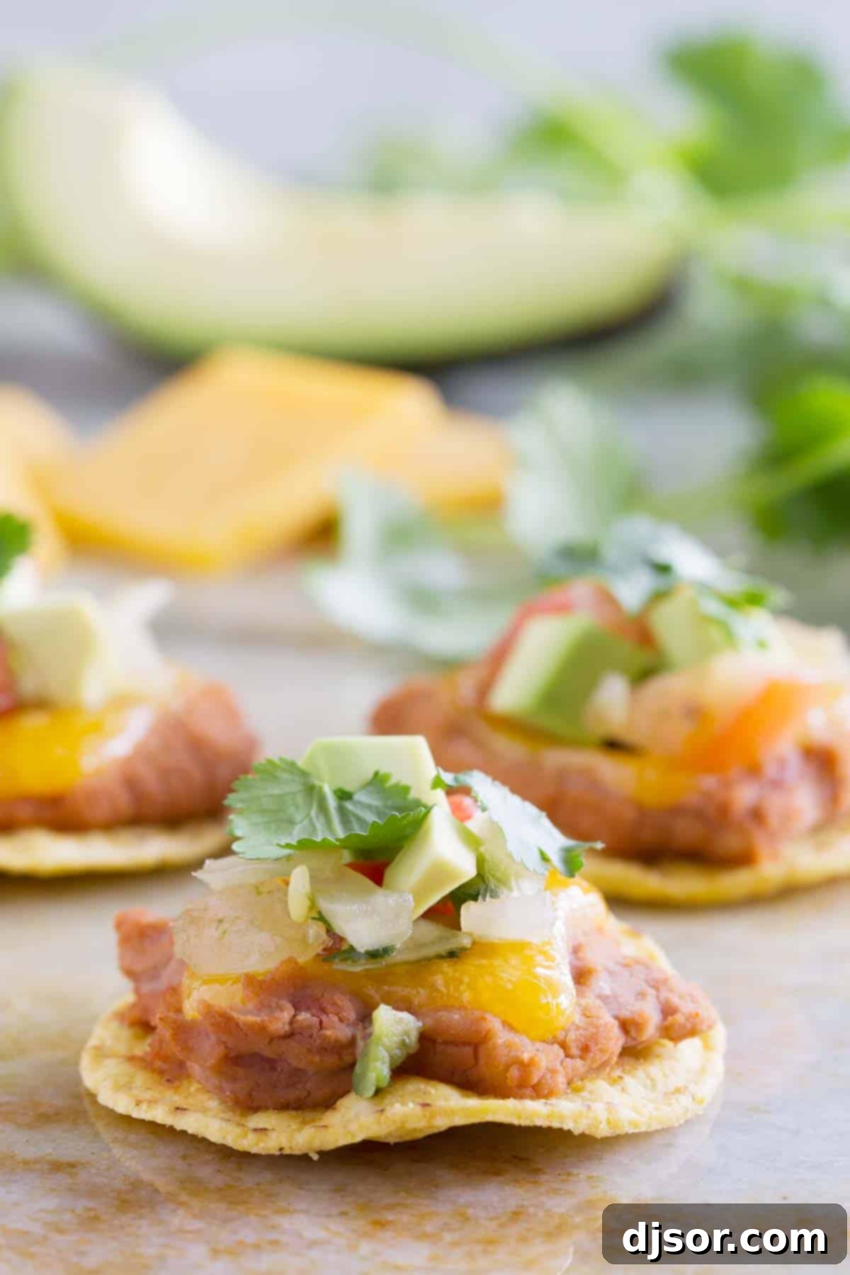 Crispy tortilla chips topped with creamy refried beans, melted cheddar cheese, and fresh pico de gallo, ready to be served as delicious Nacho Bites.