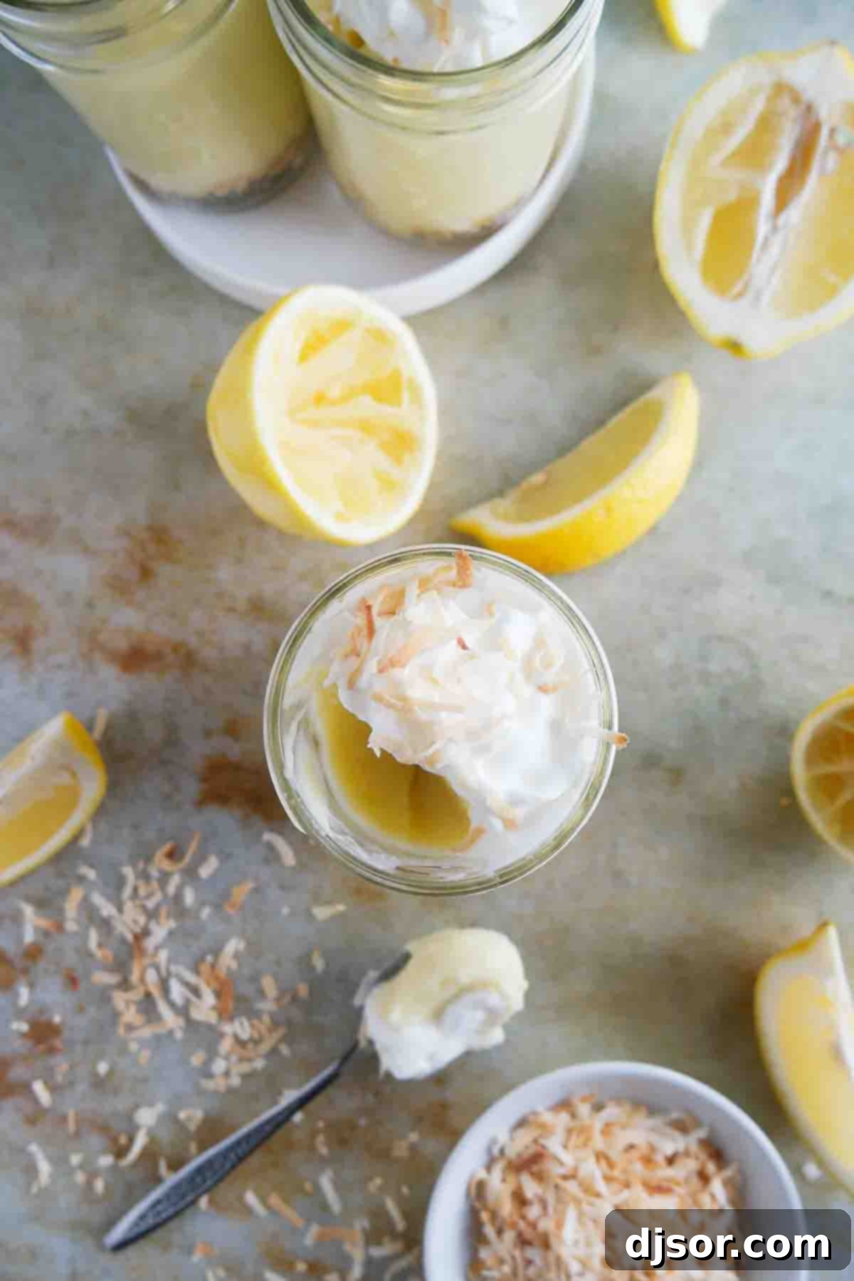 A half-eaten Coconut Lemon Pudding Parfait, topped with creamy whipped cream and toasted coconut, revealing the delicious layers within.