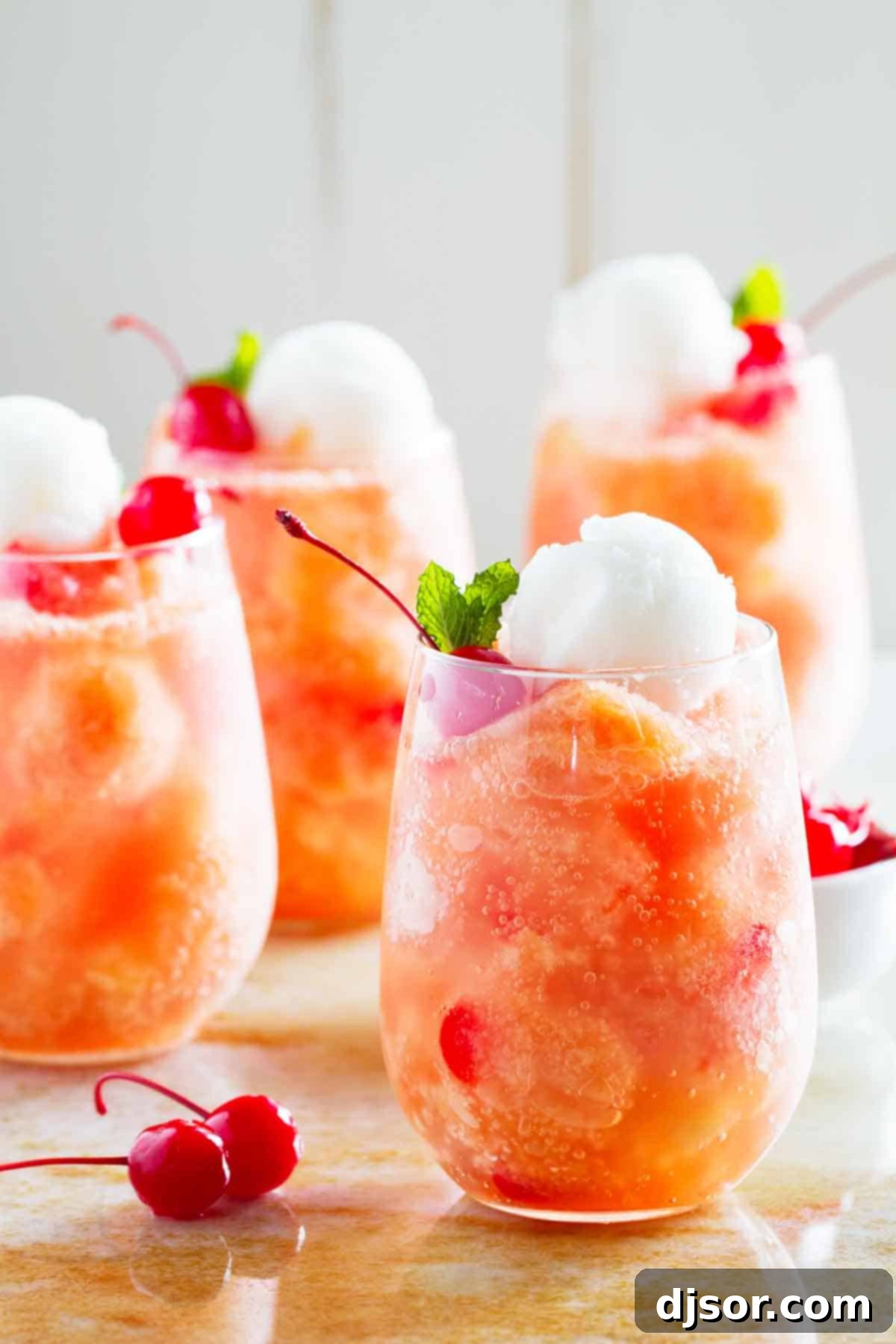 glasses of fruit freeze punch topped with sorbet and cherries, arranged artfully