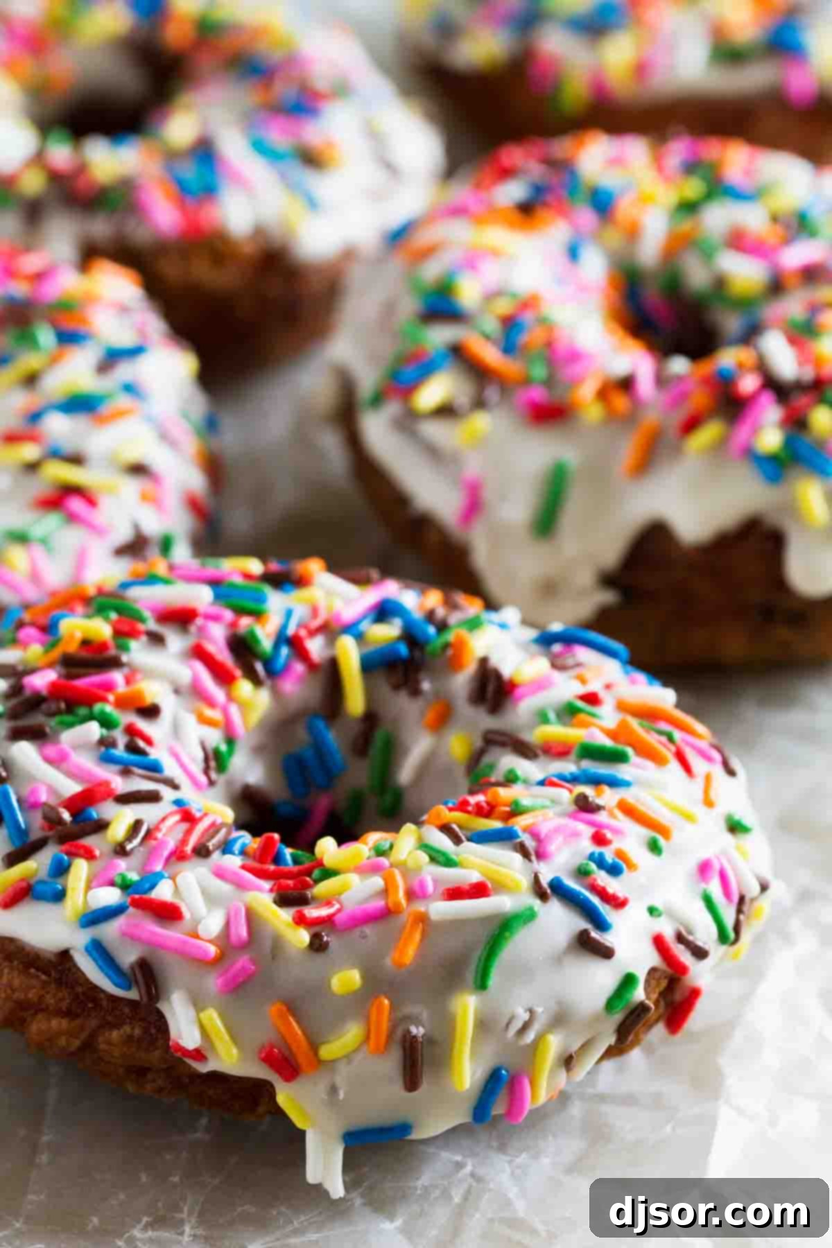 Homemade Funfetti Donuts topped with more sprinkles on a wire rack.